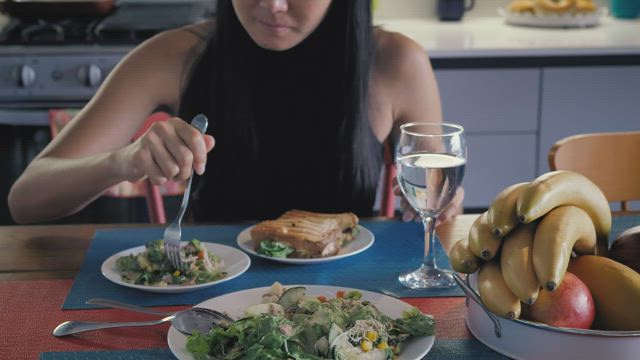 Girl eating salad in her kitchen dining room.