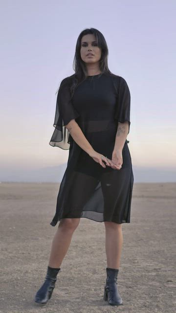 Woman posing for the camera in the middle of a desert.