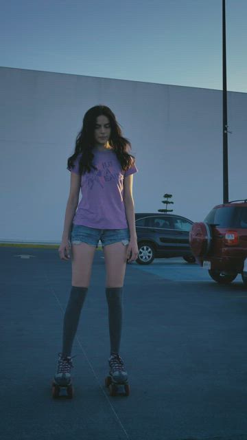 Girl gently skating in a parking lot.