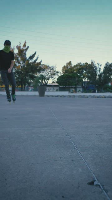 Rolling on roller skates on the ground of a parking lot.