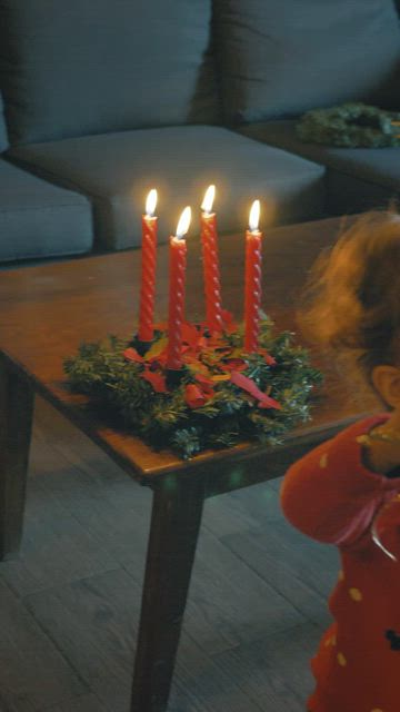 Young mother with her little daughter decorating a Christmas tree.