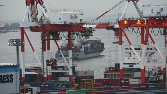 Workers moving containers from a cargo ship.