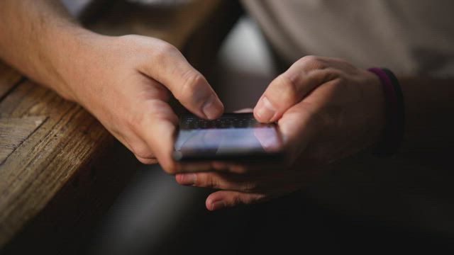 Hands of a person typing on a cell phone.