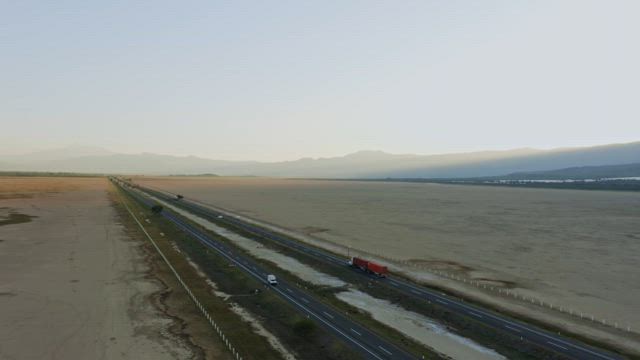 A black straight highway bustling with vehicles traverses the arid landscape.