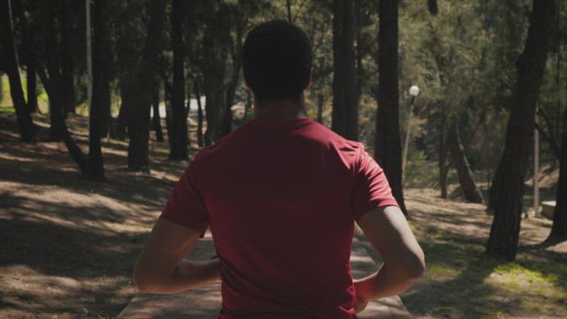 Jogging behind a man in the park.