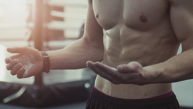 Motivated boxer claps chalked hands .